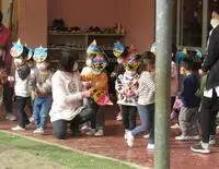 写真：先生に励まされながら豆をまく年少の子どもたち