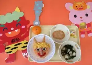 写真：給食献立 赤鬼ライス 雪ん子汁 イワシの香味フライ みかん おやつ まめまきボーロ 牛乳