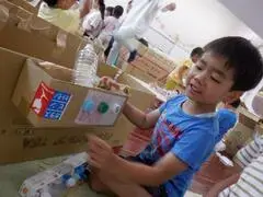 写真：ペットボトルキャップのボタンをつける子