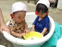 写真：たらいに入って水遊びする2人のこども