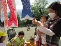 写真：保育士さんに抱っこされてこいのぼりをさわる様子