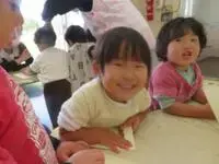 写真：テーブルに身を乗り出して笑顔の子