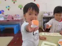 写真：絵具を付けたスタンプを自慢げに見せる子