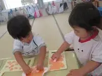 写真：二人でたくさんのスタンプを紙に押している子供たち