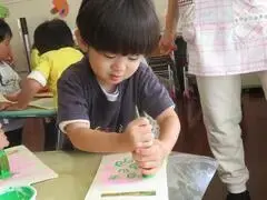 写真：緑色のスタンプを両手で一生懸命押している子