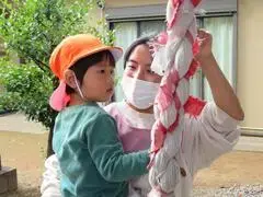 写真：先生と一緒に鈴緒を握る子