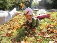 写真：落ち葉に埋もれて笑顔の子
