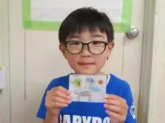 写真：完成した作品を手にもって、カメラに向けている子