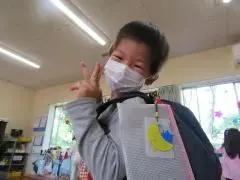 写真：リーダーの証を提げて、ピースしている子ども