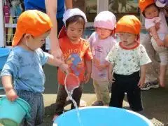 写真：バケツを手にもって水遊びをしている子