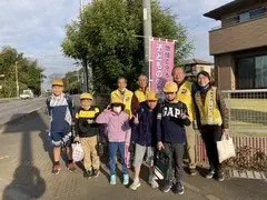 写真：挨拶運動している人たちと子供たちの集合写真