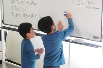 写真：ホワイトボードに書く子どもたち