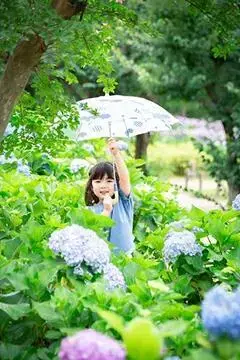 写真：四季の里公園の朝顔に囲まれて、傘を上に掲げた小さい子