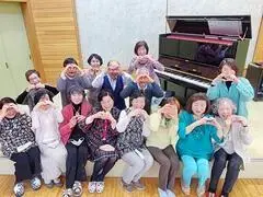 写真：ピアノをバックに手でハートの形を作り、笑顔の集合