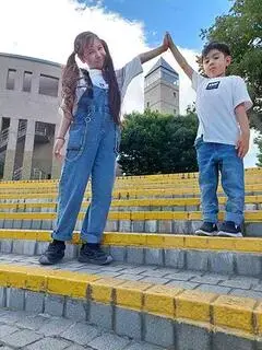 写真：市役所の中庭で、シンボルタワーのてっぺんに合わせて手を合わせている姉弟