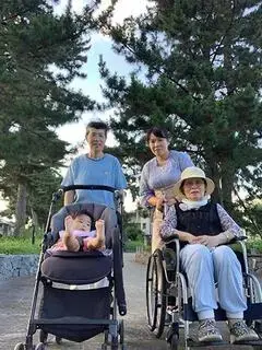 写真：松並青葉の松並木を背景に、車いすのおばあちゃん、父、娘、ベビーカーに乗った孫の四人