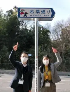 写真：若葉通りの看板とプロジェクトメンバー