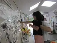 写真：先生に抱えられて高い場所を飾り付けする子