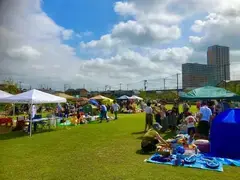 青空の下で芝生広場でフリーマーケットが開催されている様子