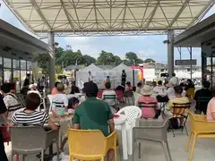 大屋根の下で椅子に座りながら音楽を聴く人たち