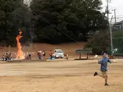 写真：どんど焼きを背景に凧揚げ