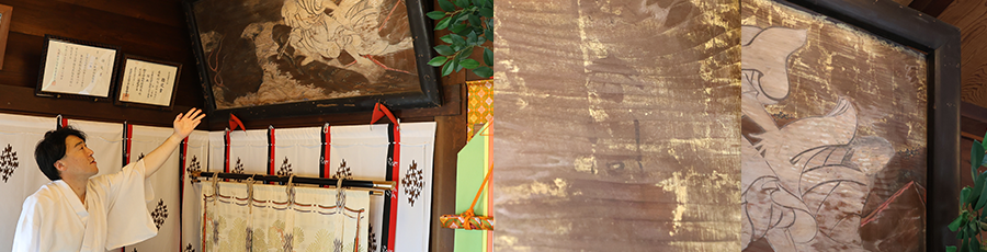 絵馬の説明をする宮司と右上部に友信の作品である「春川」が確認できる写真