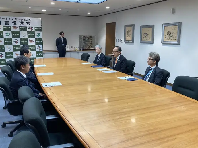 机に向かい合わせに座る国土交通大臣と松丸市長