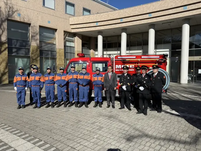 消防車を背景に記念撮影をする消防団