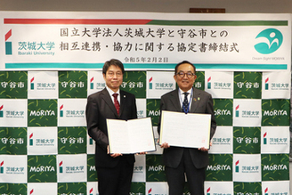 協定書を手に持ち太田寛行学長と松丸市長が二人で並んでいる