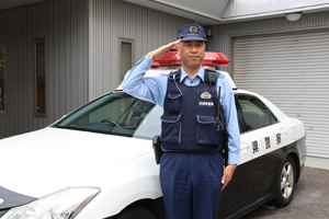 写真：パトカーと鈴木和彦さん（取手警察署地域課 守谷地区交番所長）の写真