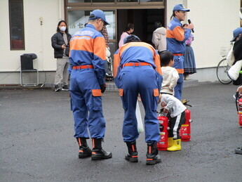 消防隊員から消火器の使い方を教わっている様子